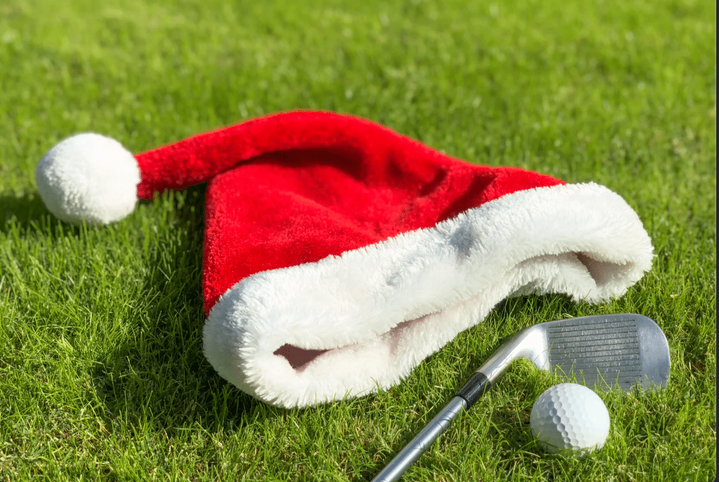 Santa's hat lying on the grass next to golf club and golfball
